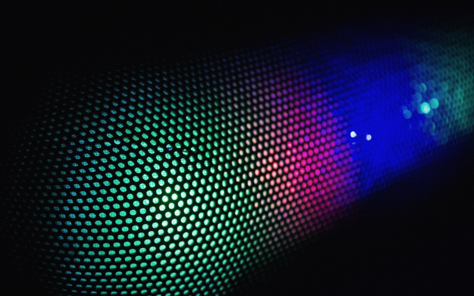 Coloured light diffracting through a fine mesh screen, shifting from green to blue and pink