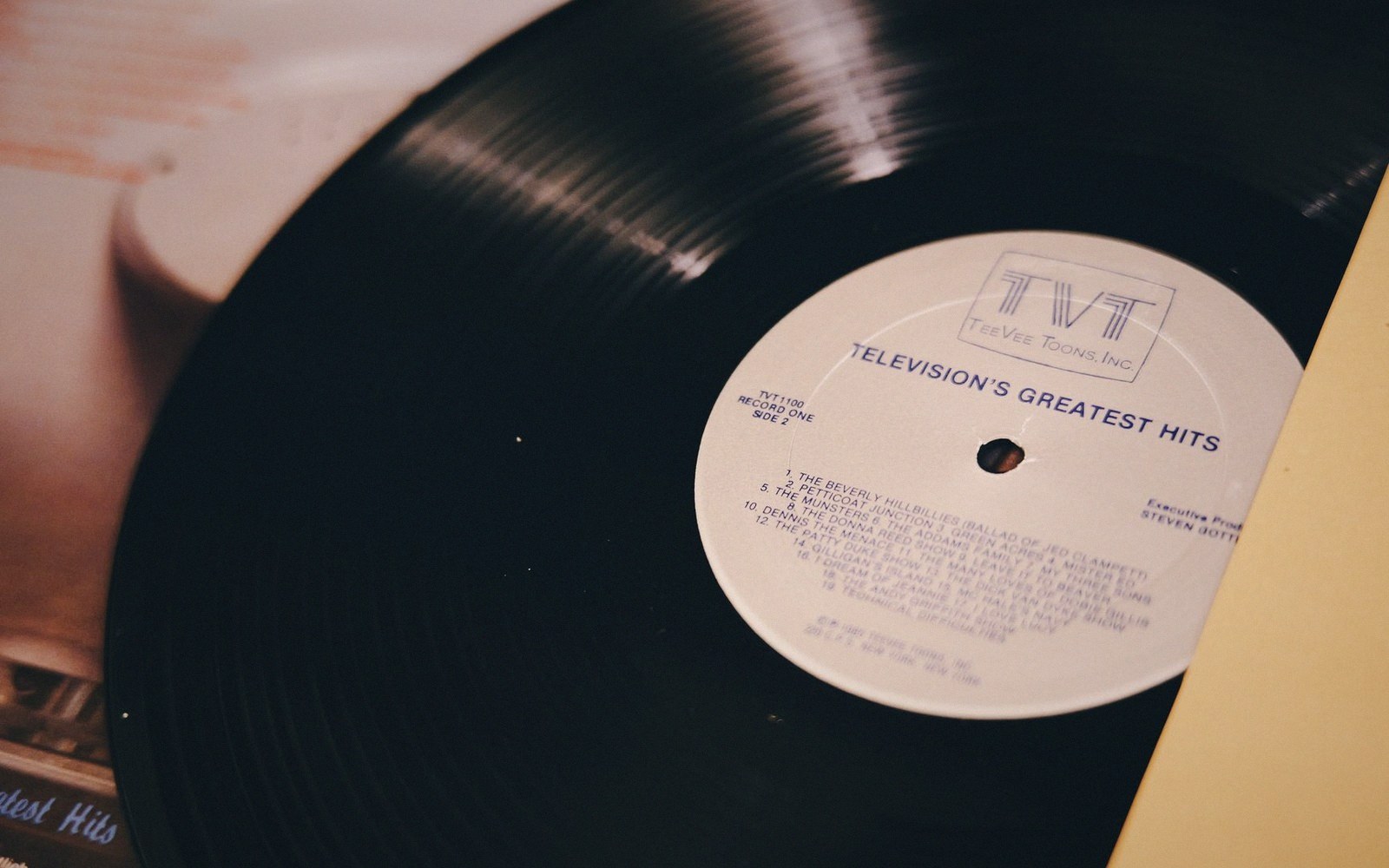 Vinyl record with a "Television's Greatest Hits" label partly resting on its sleeve