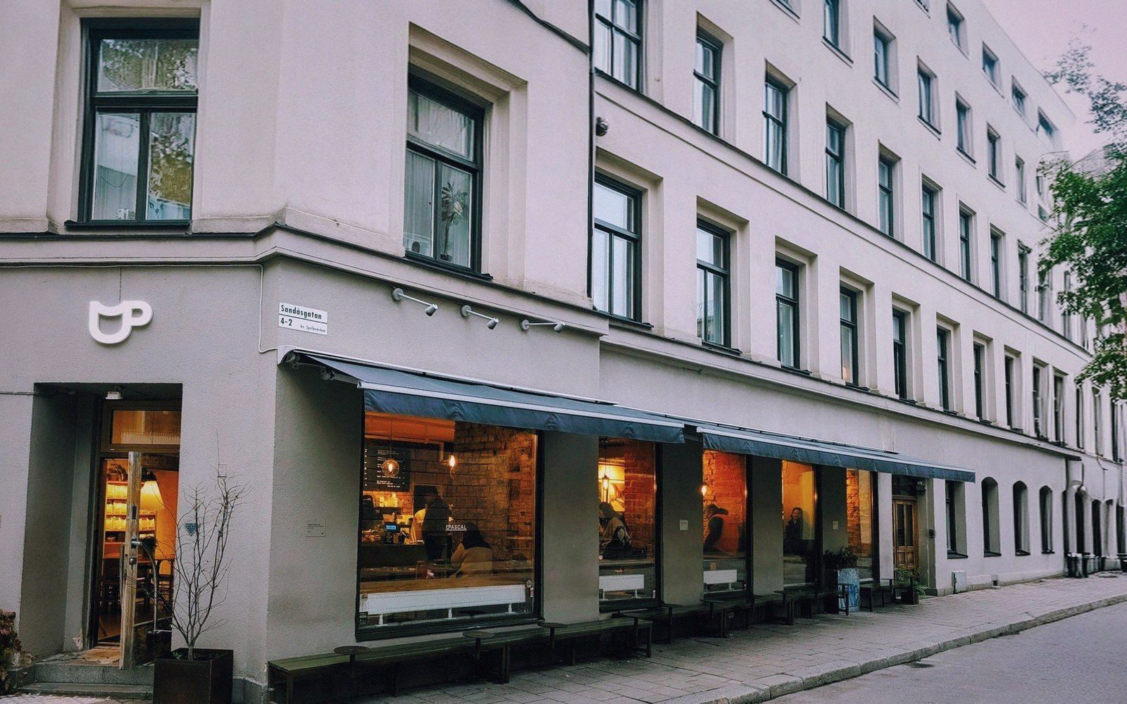 Corner cafe with striped awnings and large windows on a quiet street