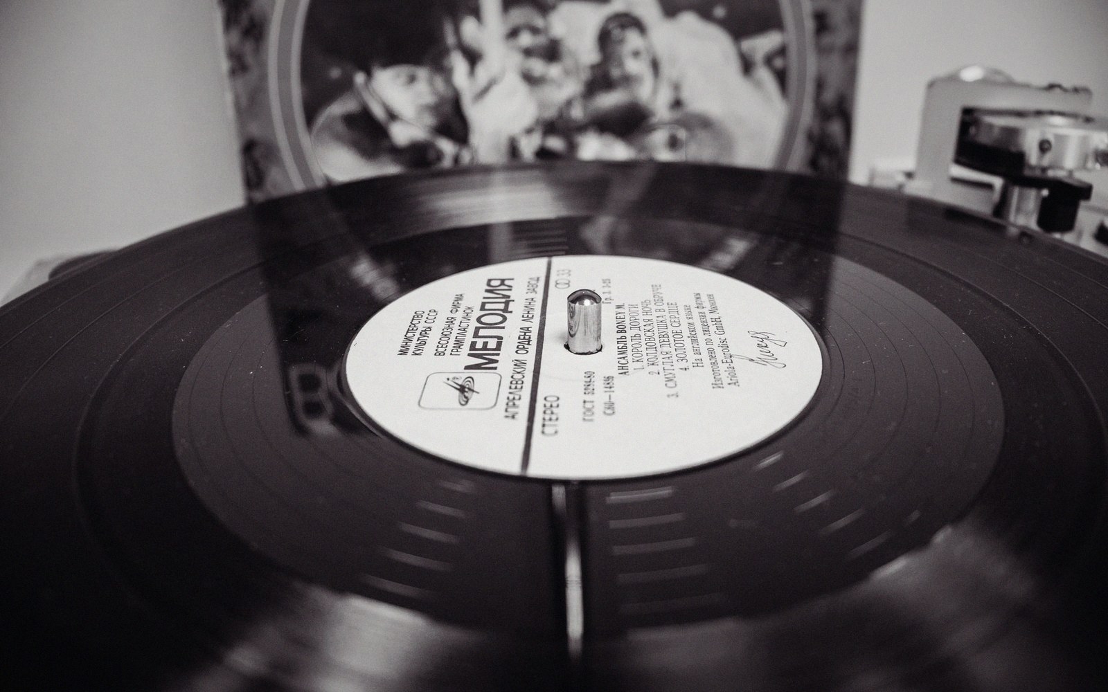 A vinyl record spinning on a turntable with its album sleeve in the background