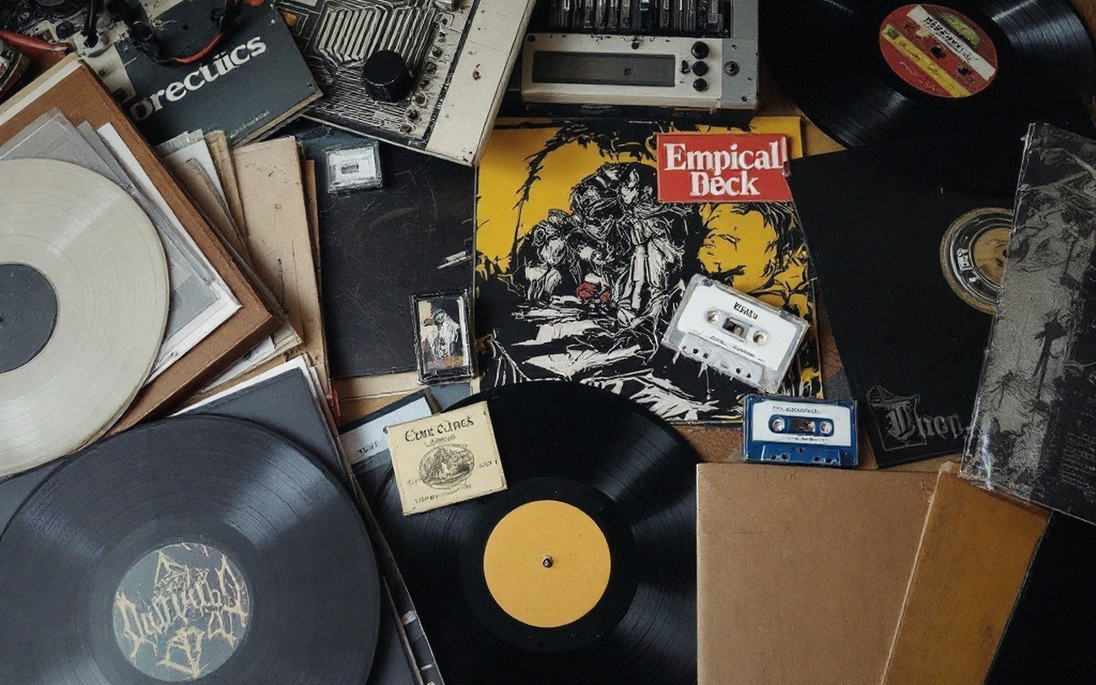 Scattered vinyl records, cassette tapes, and album sleeves piled together in a cluttered collection