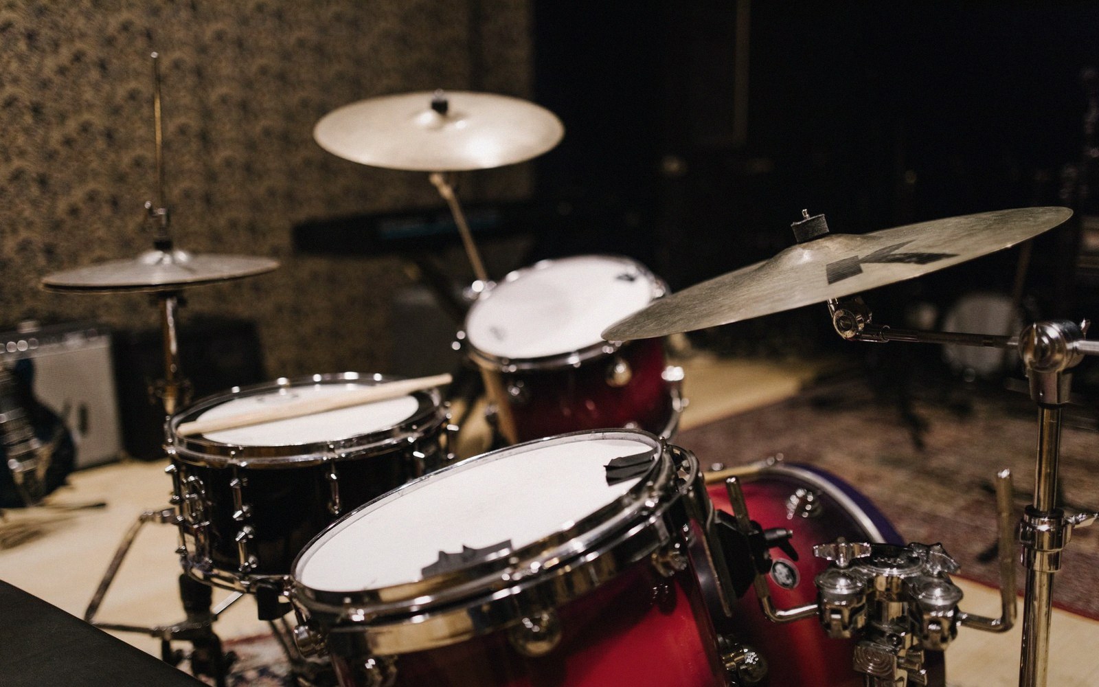 A red drum kit with cymbals and toms set up in a recording studio
