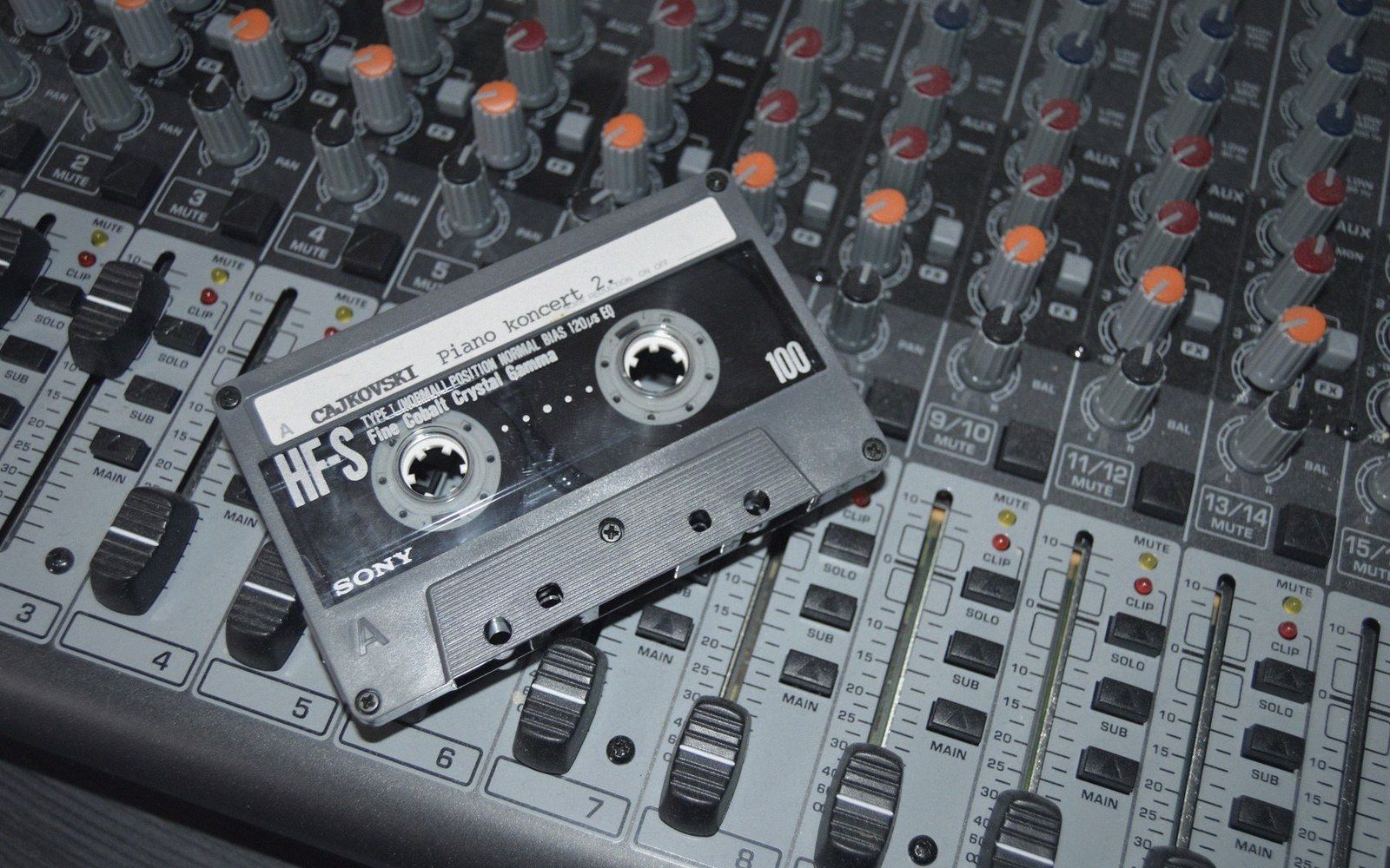 Section of an analogue mixing desk in a recording studio, faders at working positions, channel labels handwritten on masking tape