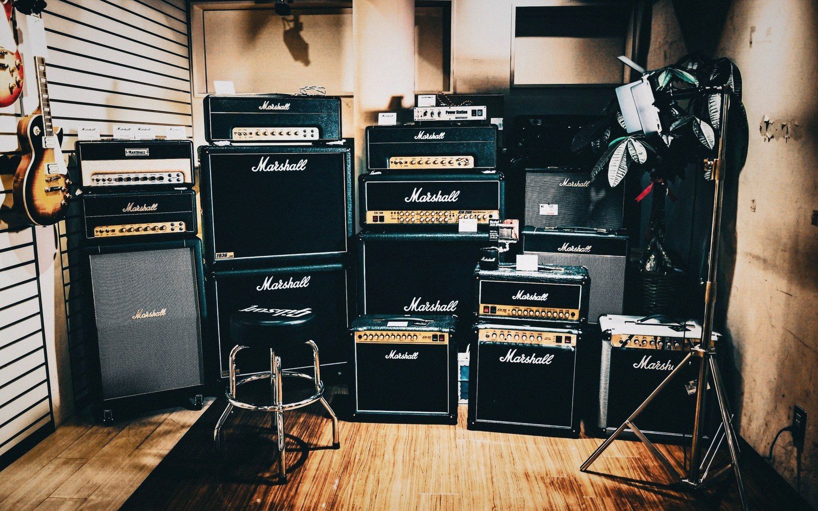 A rehearsal room with two guitar cabinets against a breeze-block wall and cables on the floor
